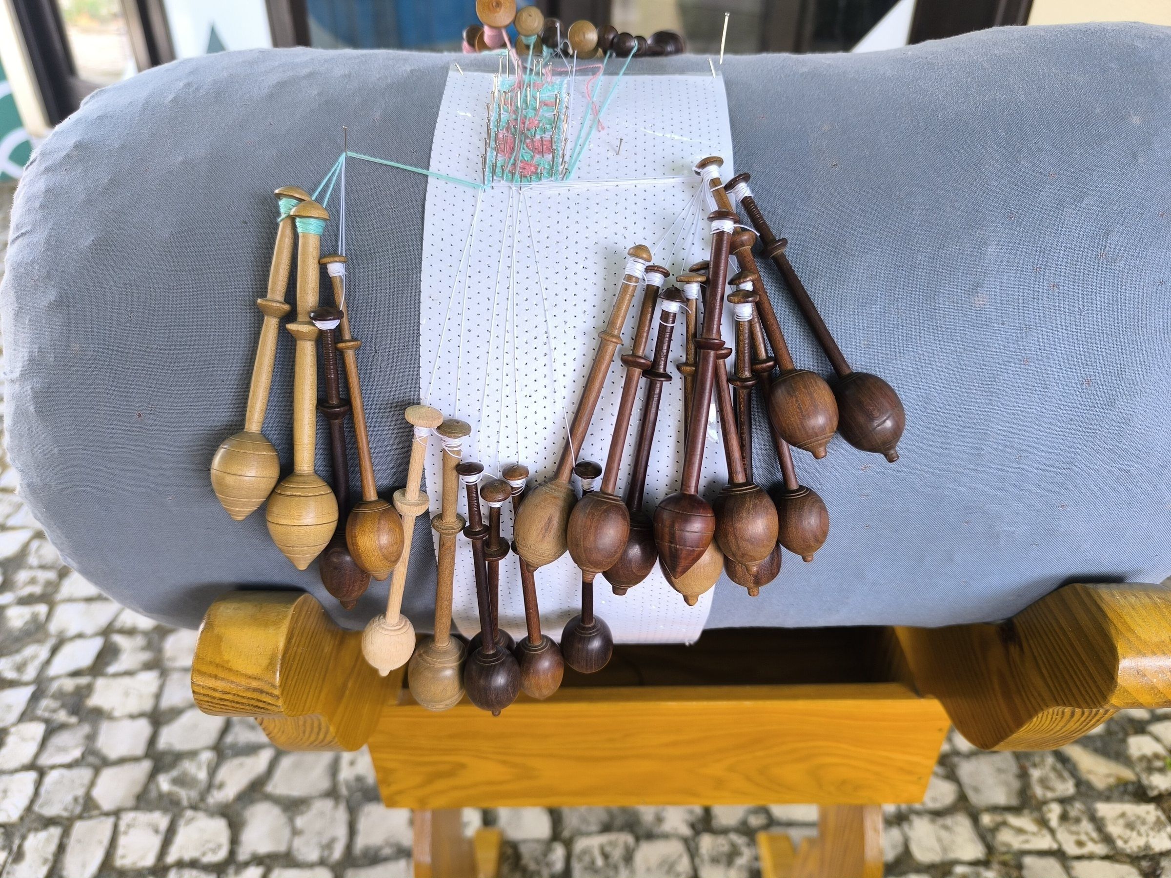Almofada com bilros de madeira e um trabalho de renda de bilro em andamento (foto feita em Peniche, Portugal)