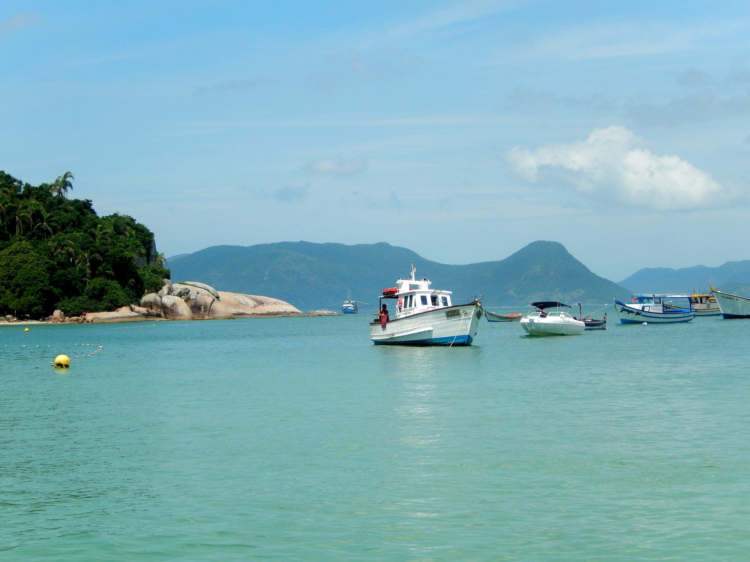 Barcos ancorados na água verde da Ilha do Campeche, com os morros do sul da ilha ao fundo