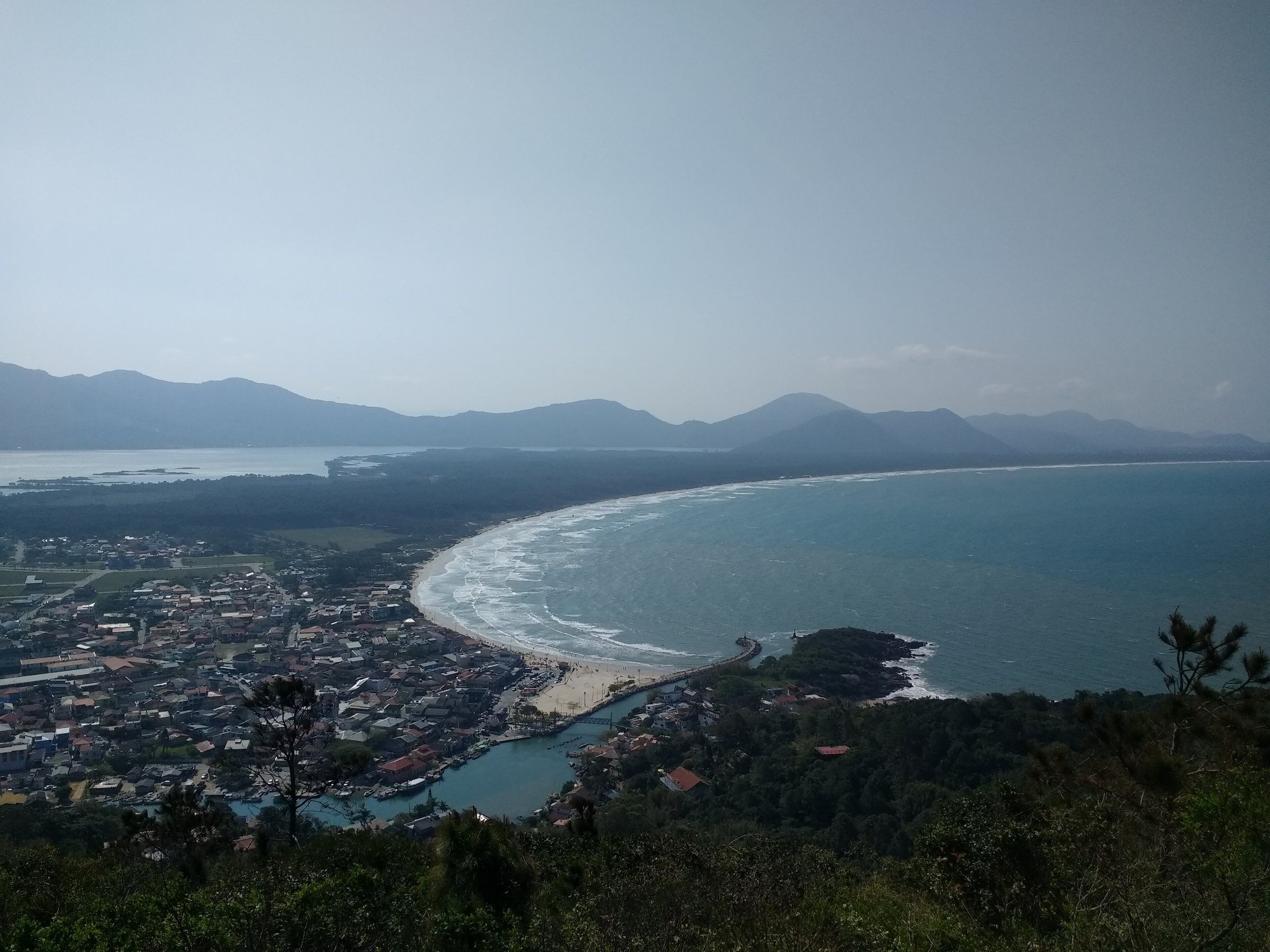 A Barra da Lagoa vista de uma trilha próxima, com a praia, o canal e o casario da vila