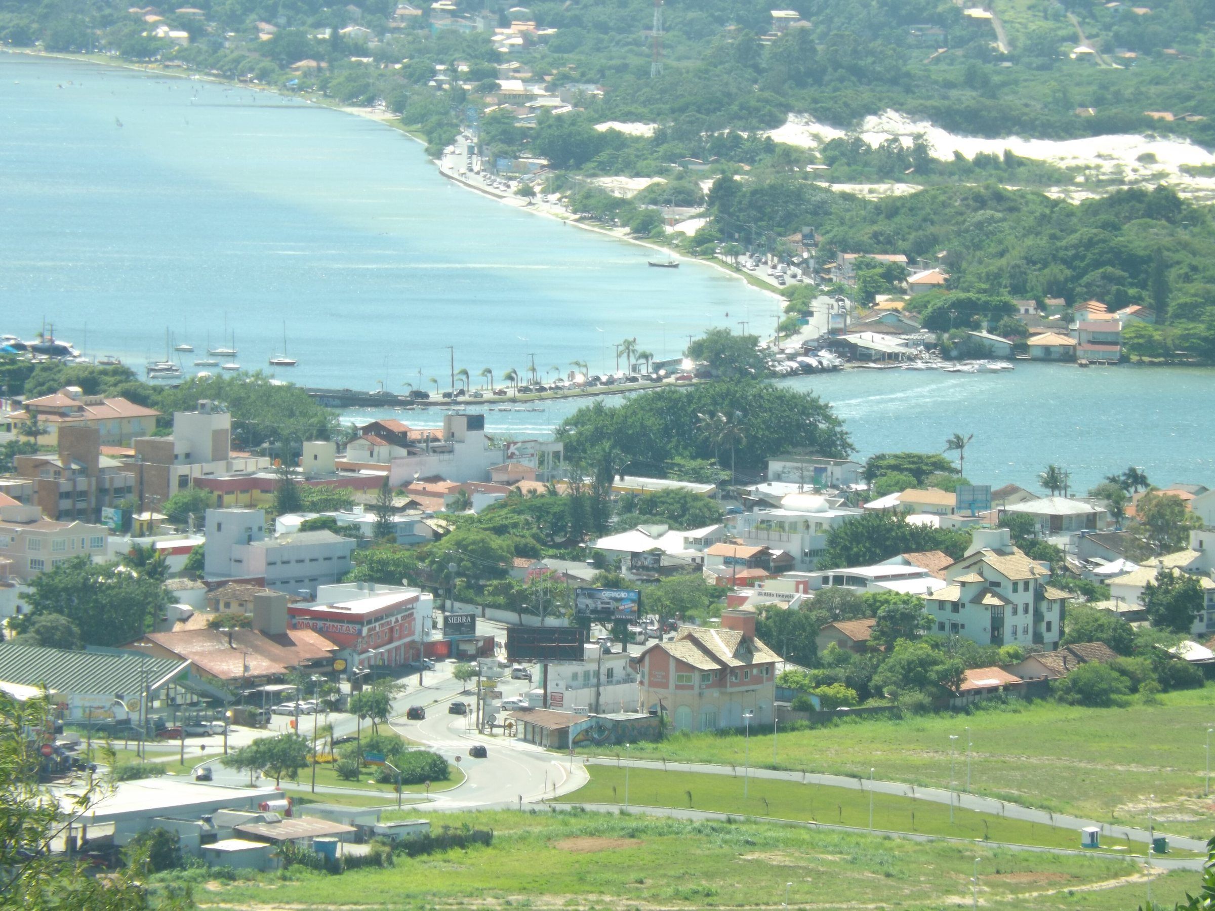 O Centrinho da Lagoa visto do alto, com a ponte, as casas, a lagoa verde-azulada e as dunas ao fundo