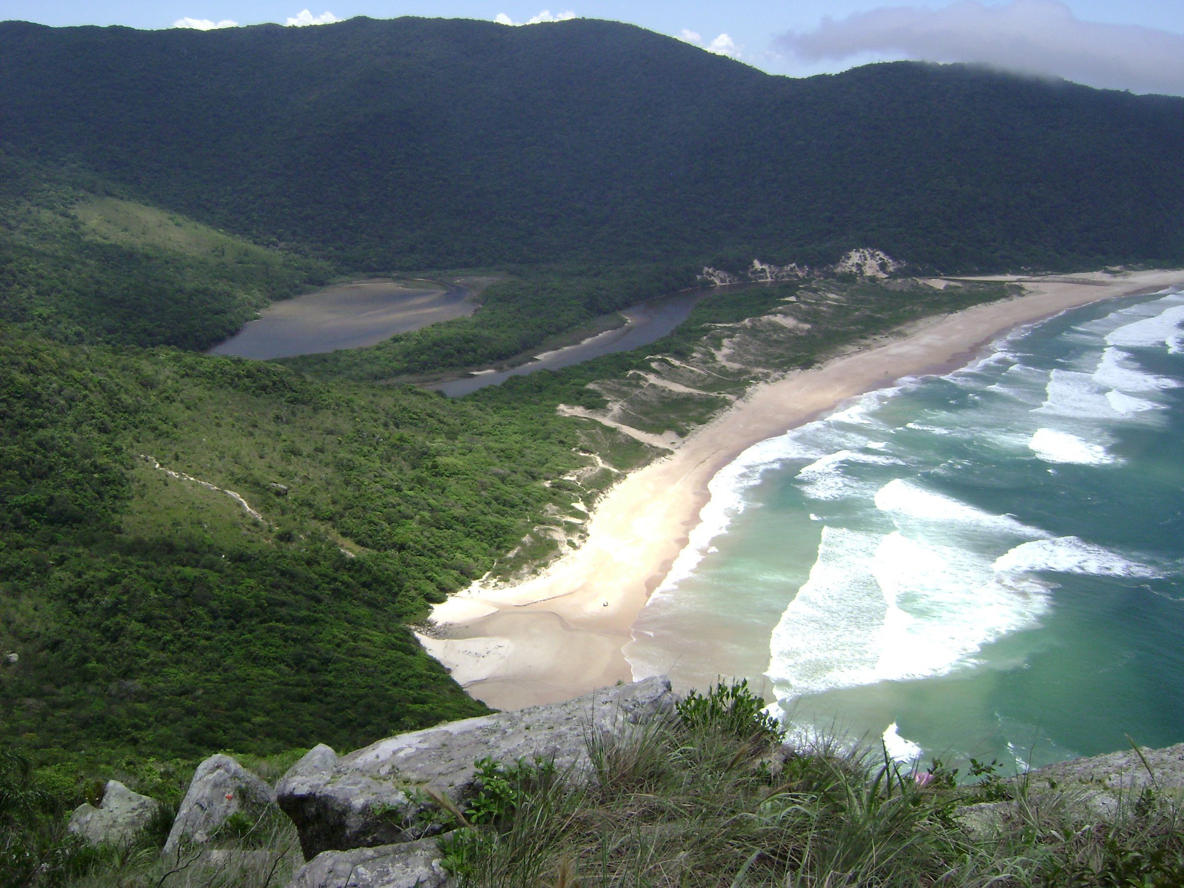 A Lagoinha do Leste vista do alto da trilha: a praia em curva, a lagoa e os morros cobertos de mata