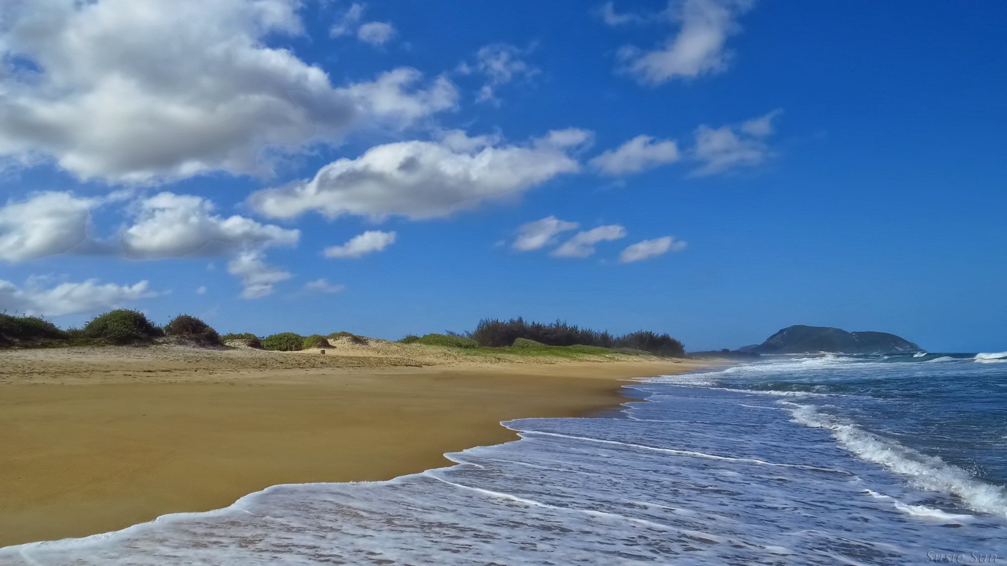 A Praia do Moçambique, longa e sem prédios, com ondas e céu de nuvens brancas