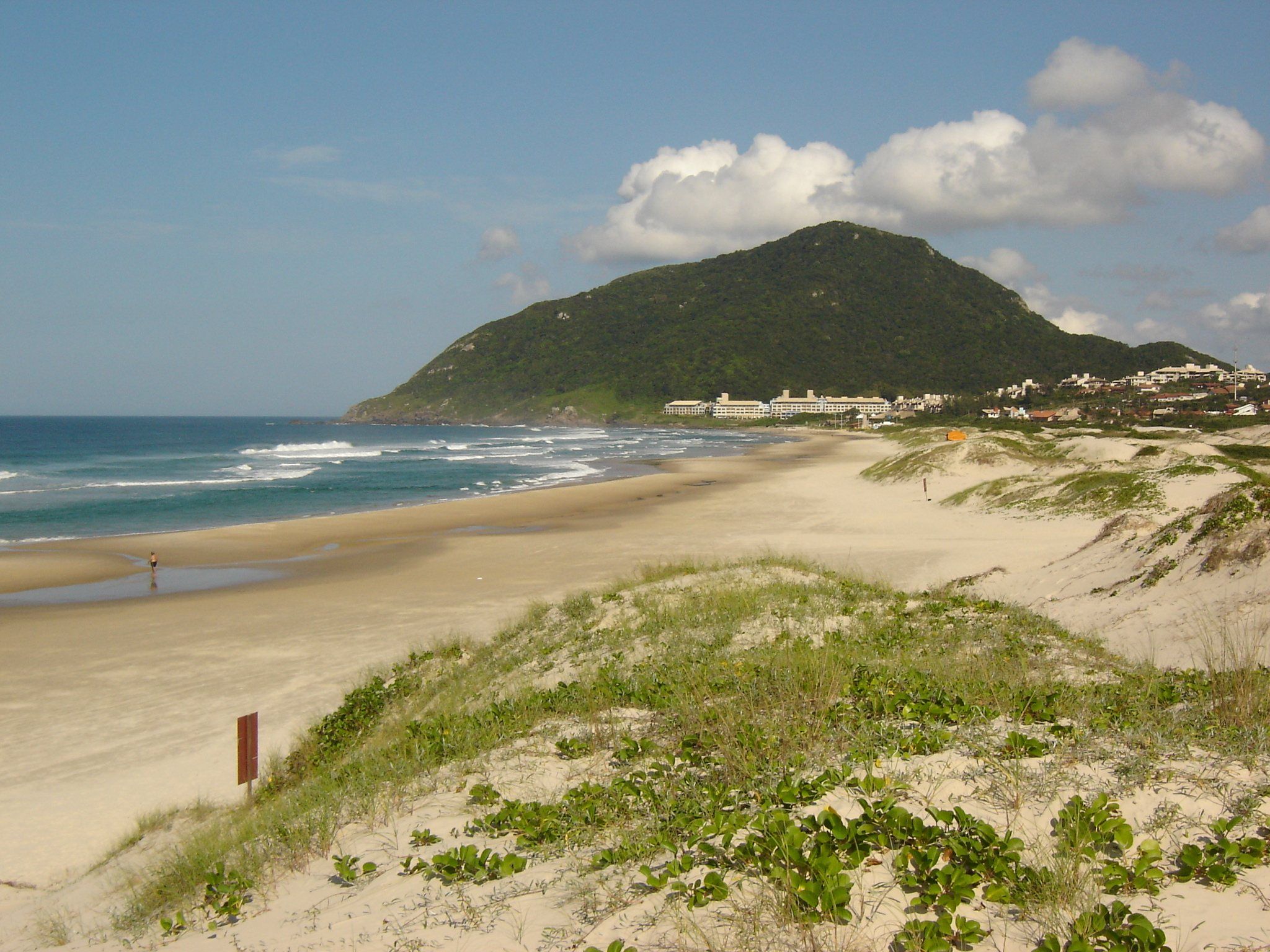 A Praia do Santinho com as dunas de restinga, a areia e o morro do costão ao fundo