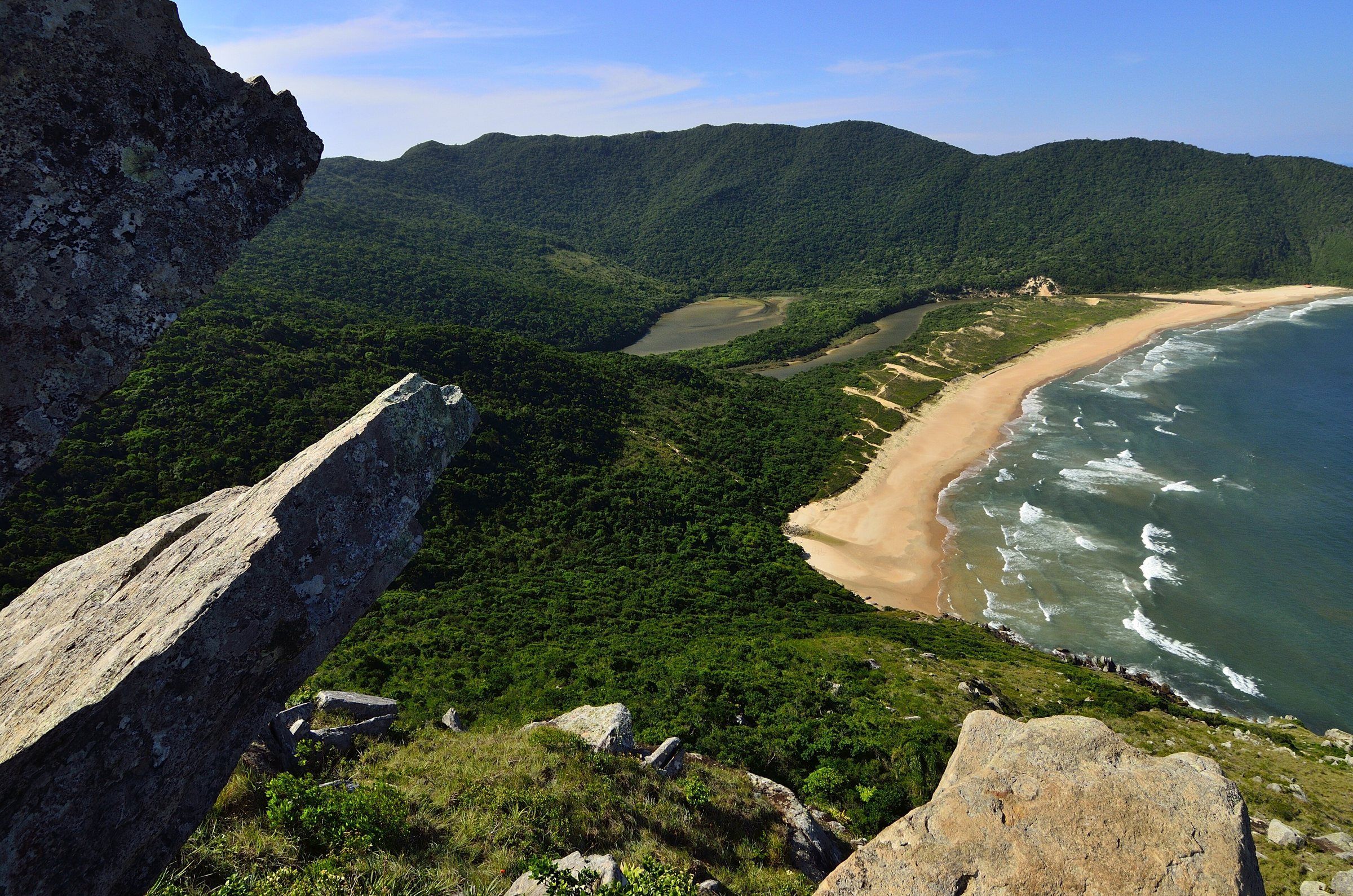 A Lagoinha do Leste vista entre pedras no alto do morro, com a faixa de areia e o mar